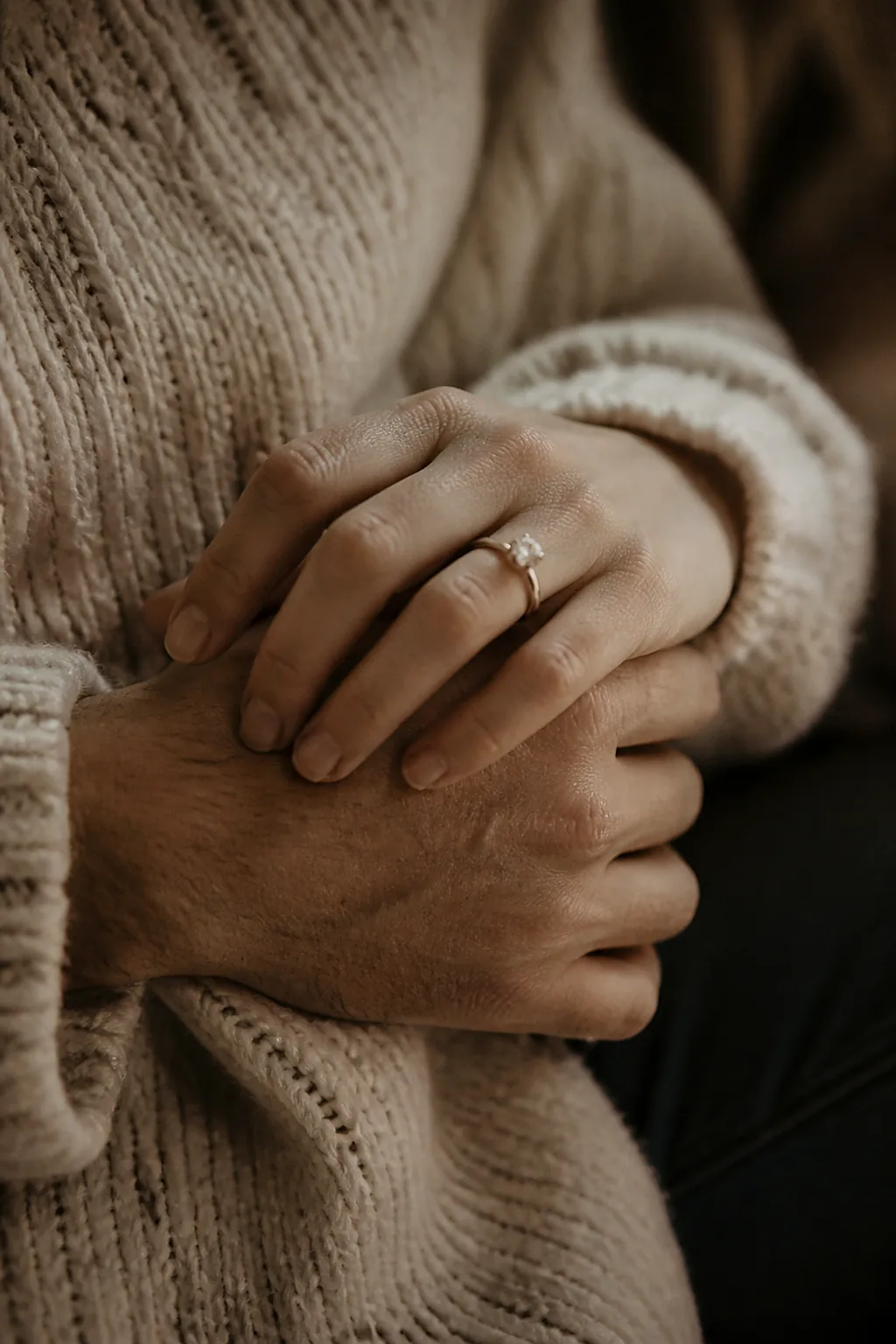 A couple’s interlaced hands with an engagement ring